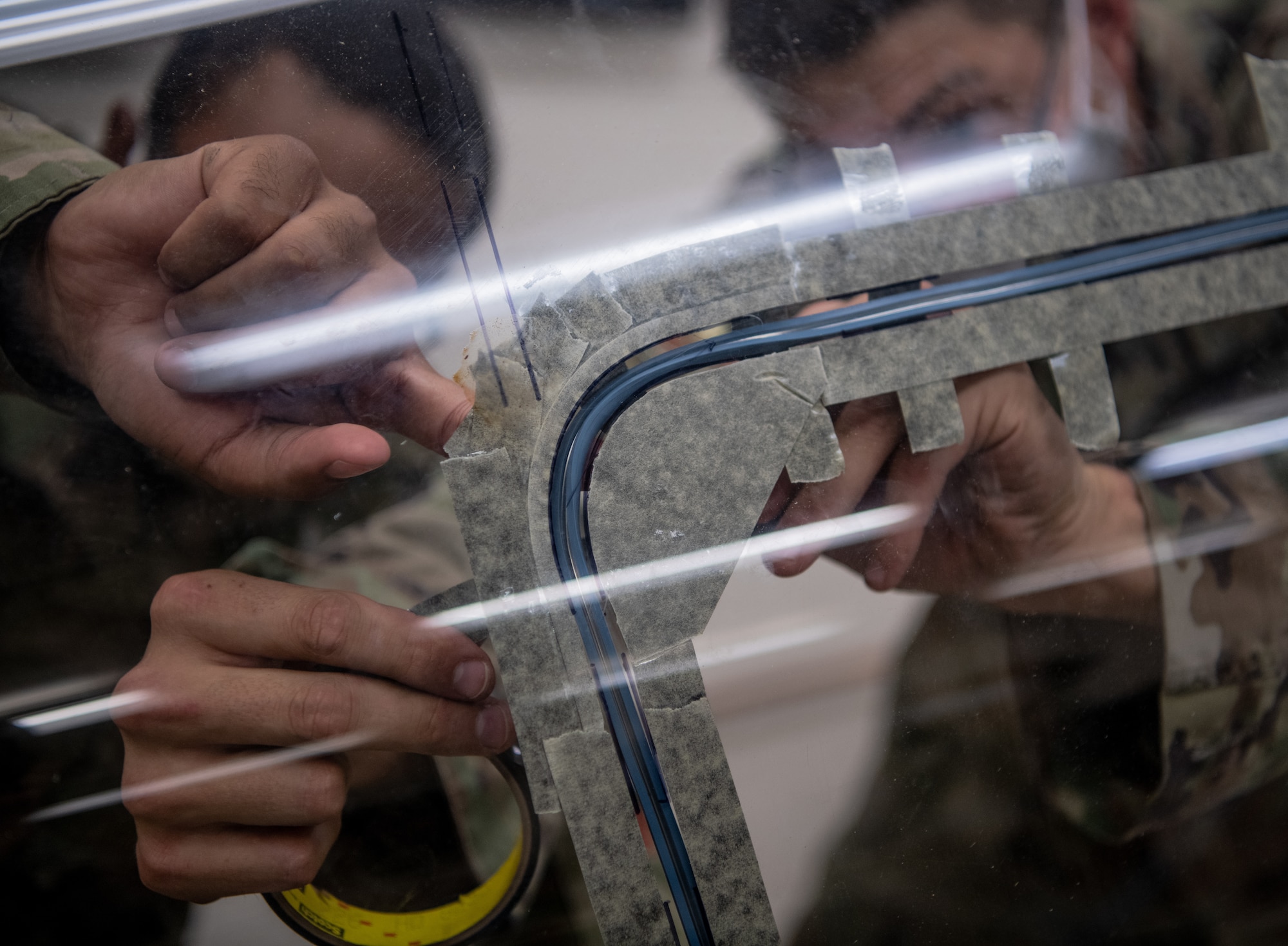 Senior Airman Matthew Romano, 56th Component Maintenance Squadron aircrew egress systems journeyman (left), trains Airman 1st Class Delwyn Travillion, 56th CMS aircrew egress systems apprentice, on the installation of flexible linear shaped charge (FLSC) on a 3D-printed F-35A Lightning II canopy July 13, 2020, at Luke Air Force Base, Ariz. The 3D print of the F-35 canopy enables training on the installation of the FLSC without using operational resources. Installation of the FLSC is an essential task that requires zero errors. (U.S. Air Force photo by Airman 1st Class Dominic Tyler)