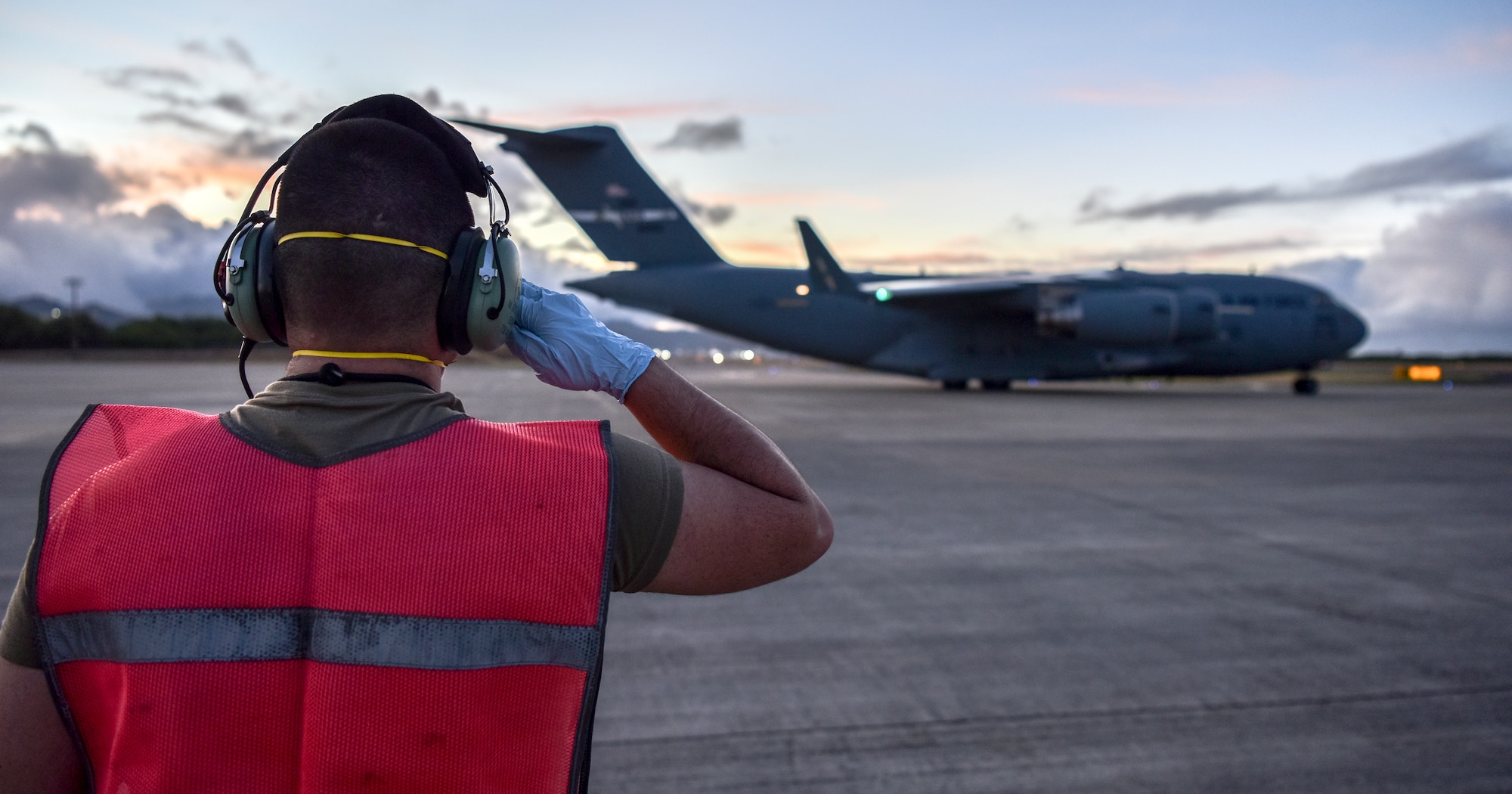 U.S. Air Force Staff Sgt. Michael Bonilla, 735th Air Mobility Squadron craftsman, salutes a C-17 from Travis Air Force Base, California as it departs the Hickam Field flight line in support of a Transport Isolation System operation at Joint Base Pearl-Harbor Hickam, Hawaii, July 17, 2020. Several U.S. Air Force units came together to rapidly deploy the bio-containment capability for the first time in the Indo-Pacific theater in support of a COVID-19 aeromedical evacuation mission. The TIS is an infectious disease containment unit designed to minimize contamination risk to aircrew and medical attendants, while allowing in-flight medical care for patients afflicted by a disease. (U.S. Air Force photo by Tech. Sgt. Anthony Nelson Jr.)