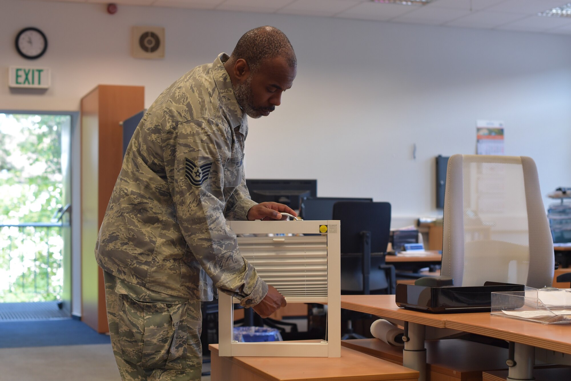 An Airman pulls a window blind down.