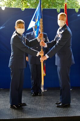 Photo of two Airmen passing a guidon.