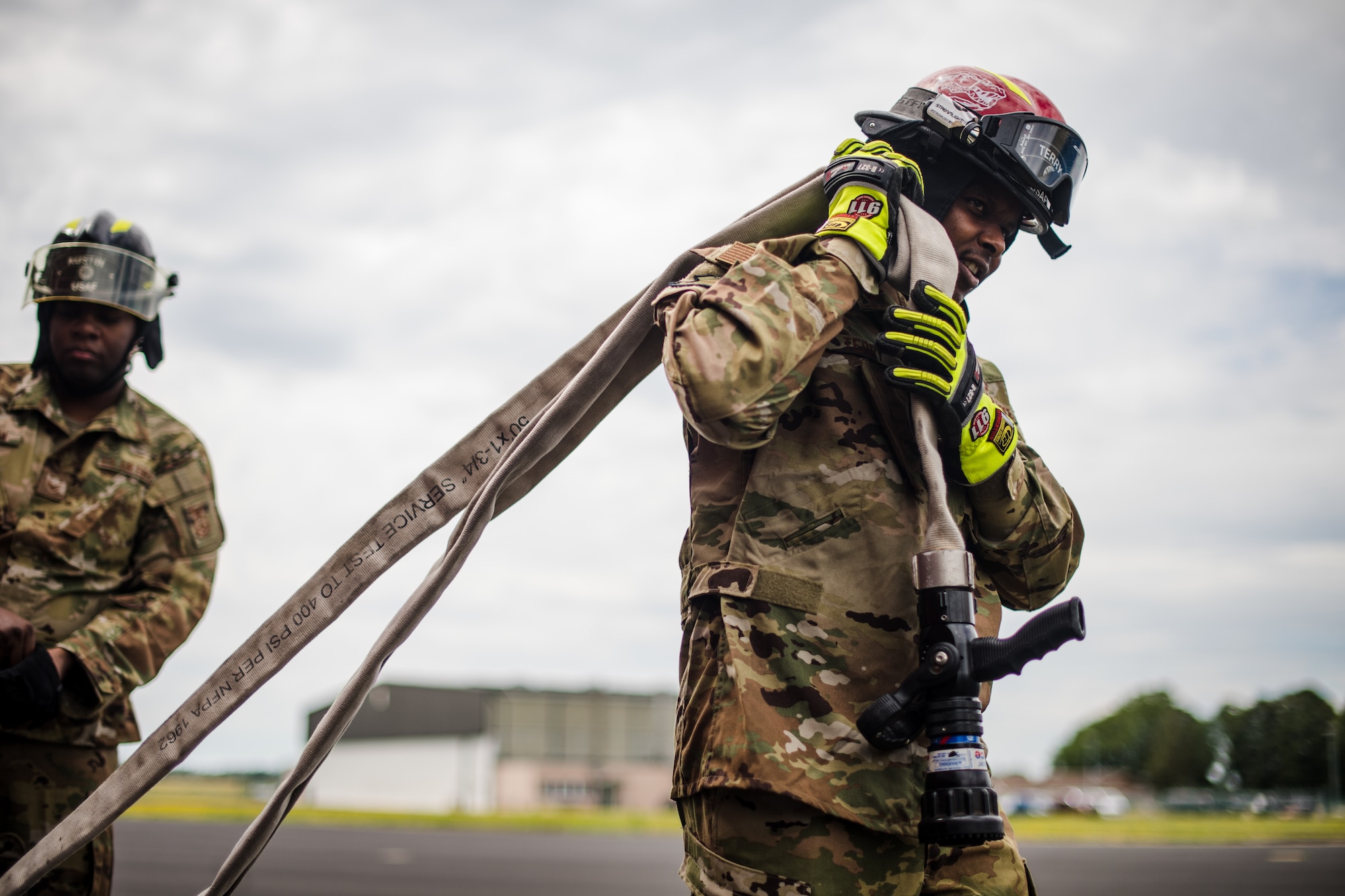 Photo of Air Force firefighter carrying hose