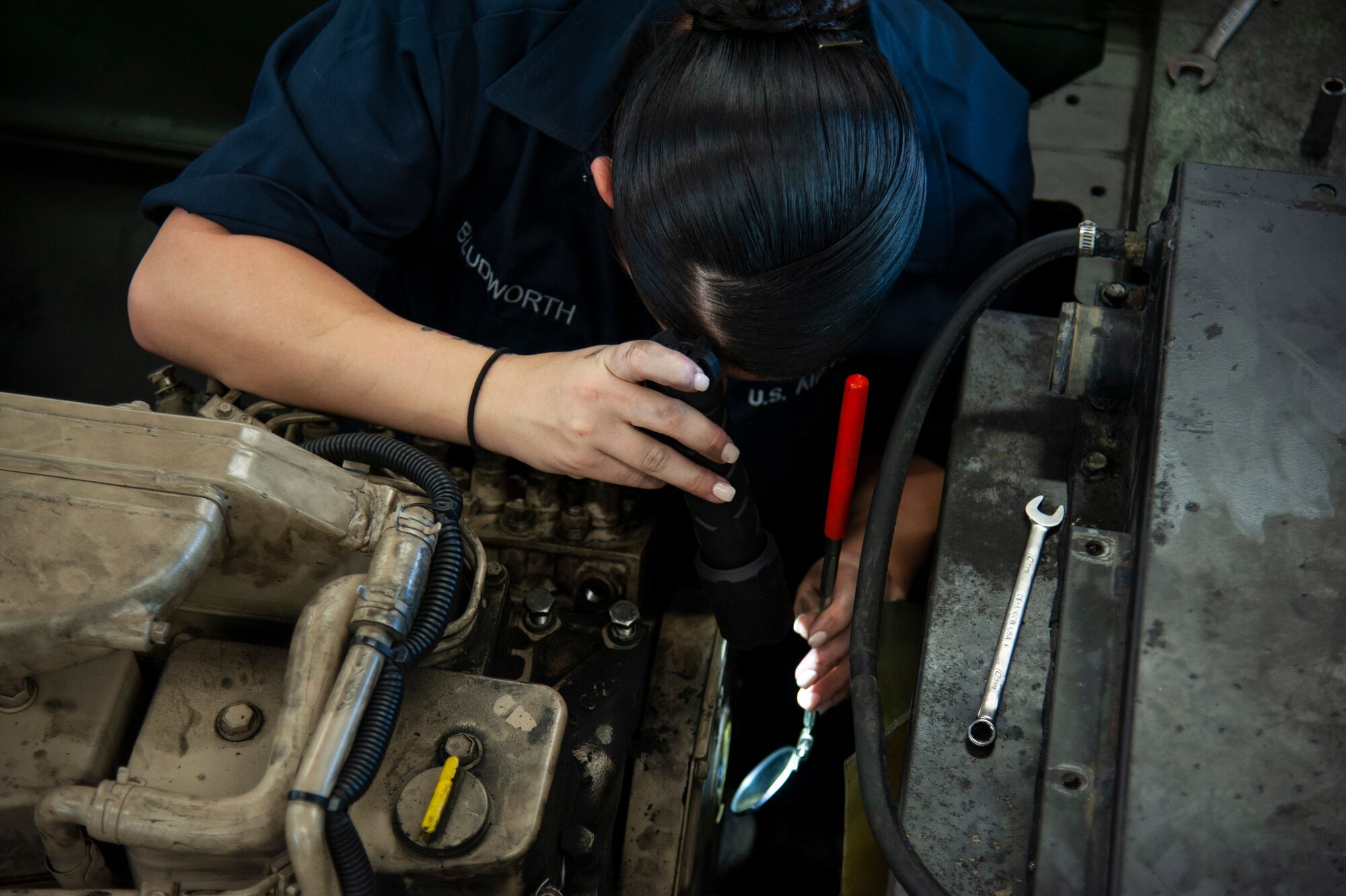 U.S. Air Force Staff Sgt. Virginia Bludworth, a 6th Logistics Readiness Squadron vehicle mechanic, uses a flashlight and inspection mirror to view the fuel injection pump on an MB-2 aircraft tow tractor, July 15, 2020, at MacDill Air Force Base, Fla.