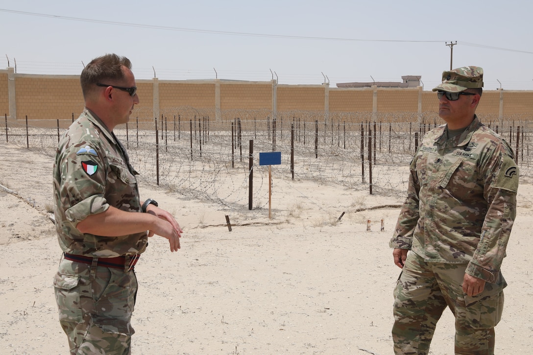 U.S. Army Lt. Col. Michael Rodriguez receives an orientation to the training lanes of the Kuwait Land Forces Engineer School by British Army Warrant Officer two Andrew Foley. The lanes are set up to show engineers how to overcome or set up obstacles.