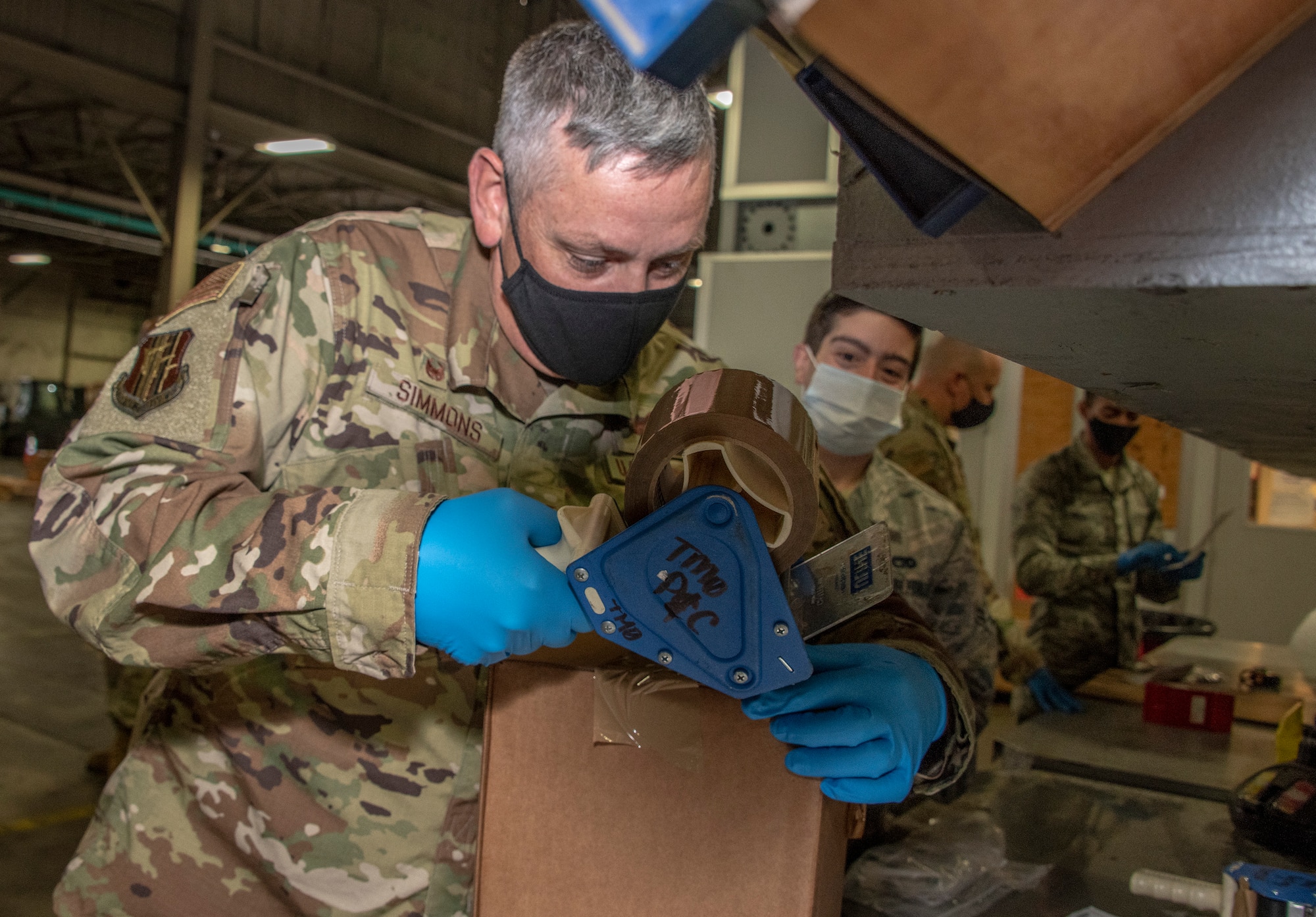 U.S. Air Force Col. Corey Simmons, left, 60th Air Mobility Wing commander, tapes up a shipment box as Airman 1st Class Gregory Concilla, 60th Aerial Port Squadron packing and crating technician, watches during Leadership Rounds July 24, 2020, at Travis Air Force Base, California. The 60th APS is the United States Transportation Command's primary west coast aerial port providing global and passenger distribution for the United States and its Allies. The Leadership Rounds program provides 60th AMW leadership an opportunity to interact with Airmen and get a detailed view of each mission performed at Travis AFB. (U.S. Air Force photo by Heide Couch)