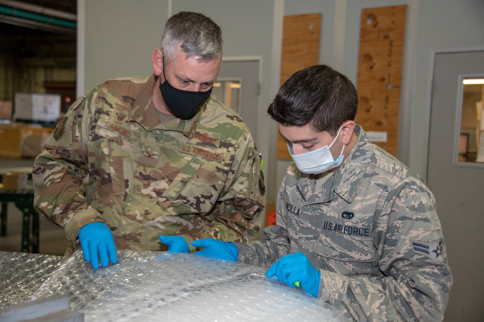 U.S. Air Force Col. Corey Simmons, left, 60th Air Mobility Wing commander, and Airman 1st Class Gregory Concilla, 60th Aerial Port Squadron packing and crating technician, measure packing material during Leadership Rounds July 24, 2020, at Travis Air Force Base, California. The 60th APS is the United States Transportation Command's primary west coast aerial port providing global and passenger distribution for the United States and its Allies. The Leadership Rounds program provides 60th AMW leadership an opportunity to interact with Airmen and get a detailed view of each mission performed at Travis AFB. (U.S. Air Force photo by Heide Couch)