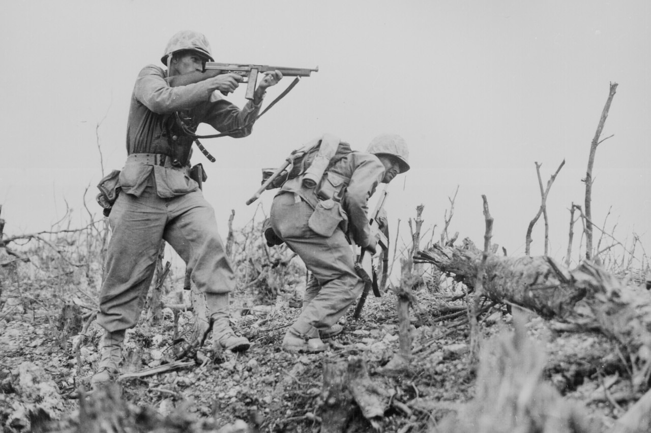 A Marine aims his weapon while another Marine looks for cover.