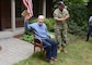 Capt. Thomas J. Hudner sitting in a chair shows off his birthday gift, a plaque made of USS Constitution wood and copper