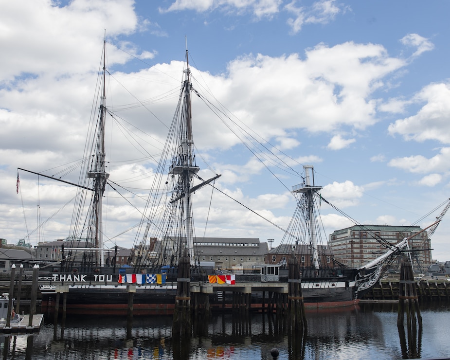 USS Constitution is docked in Charlestown, behind a "thank you". message, written by the crew in wooden letters and signal flags