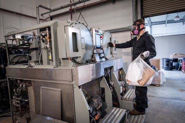 Peter Mech, an engineer with Naval Surface Warfare Center, Carderock Division’s Environmental Engineering, Science, and Technology Branch, loads the Micro-Auto Gasification System (MAGS) incinerator to thermally destroy solid waste on May 10,
