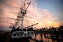 The ship is docked with beautiful sunset in the background along with Boston skyline