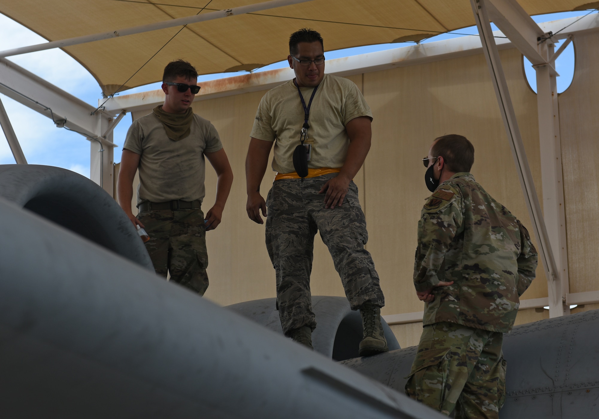 Photo of a military chaplain talking to two maintainers on top of an A-10 Thunderbolt II at the Davis-Monthan Air Force Base flightline