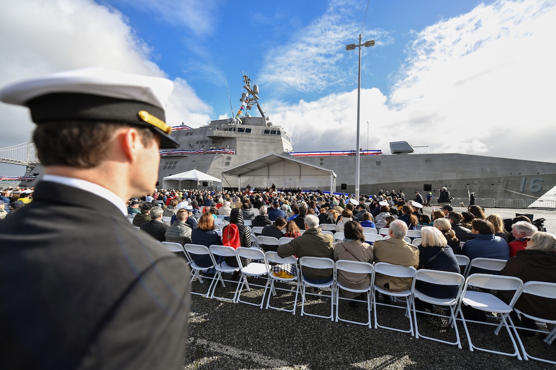 Commission ceremony showing the ship in background as guests sit, listening