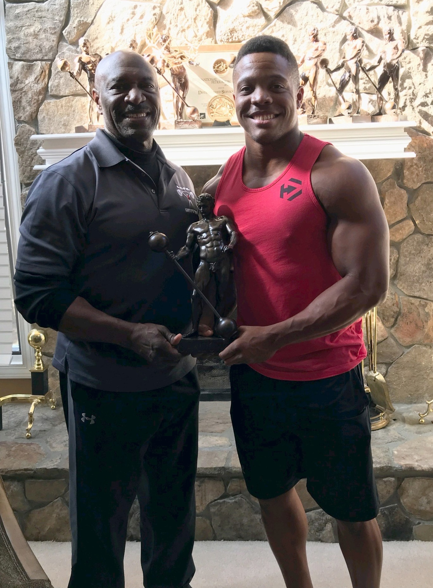 Staff Sgt. Geremy Satcher takes a photo with eight-time Mr. Olympia, Lee Haney as they hold one of his trophies. Haney became a mentor for Satcher when he was a body builder.
