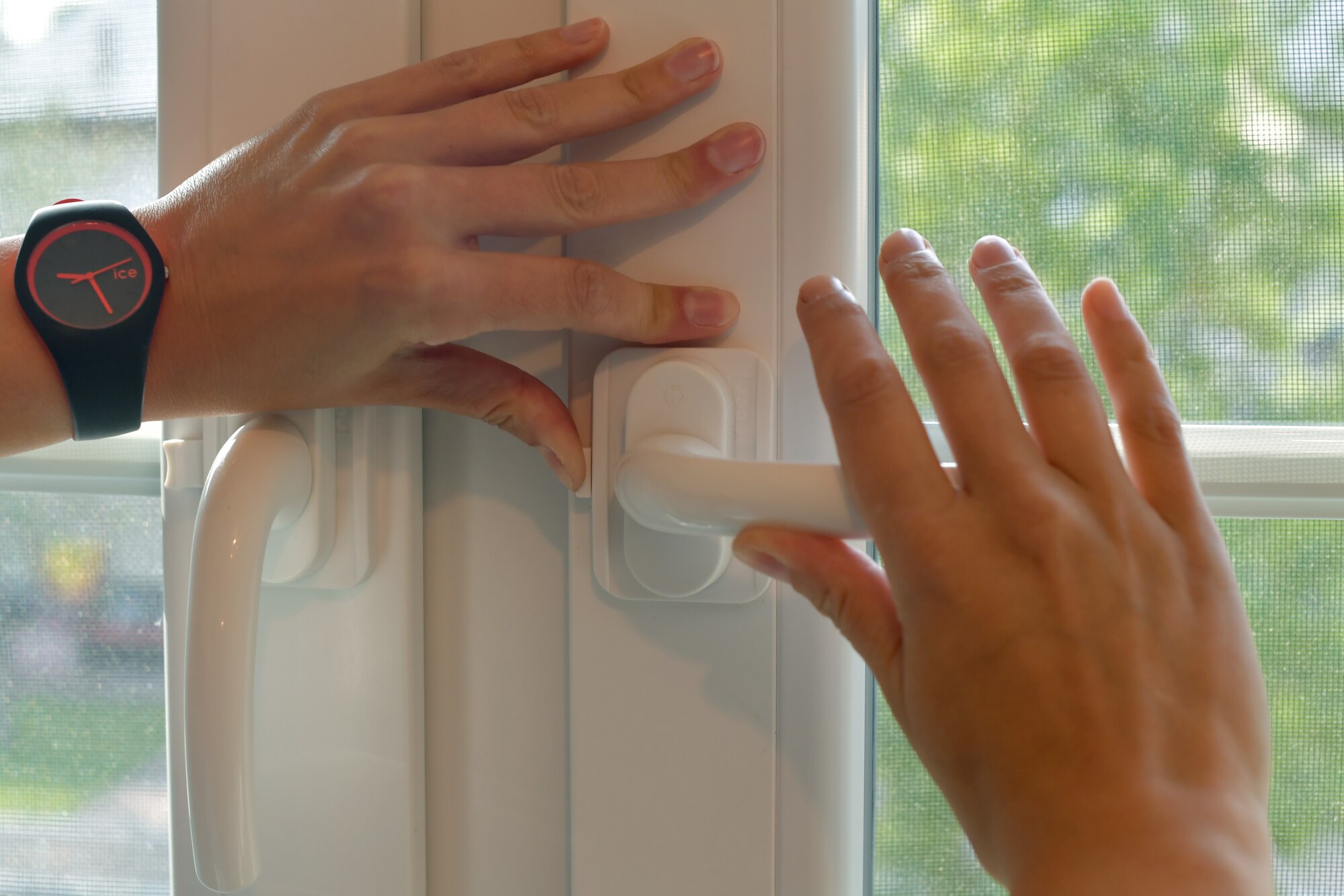 A person's hands turning the handle to open a window.