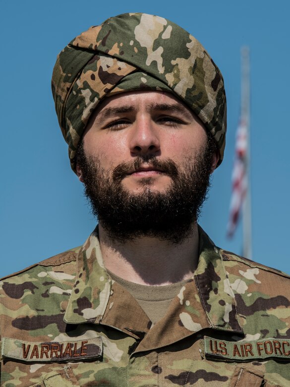 One man standing outside with a flag in the background.
