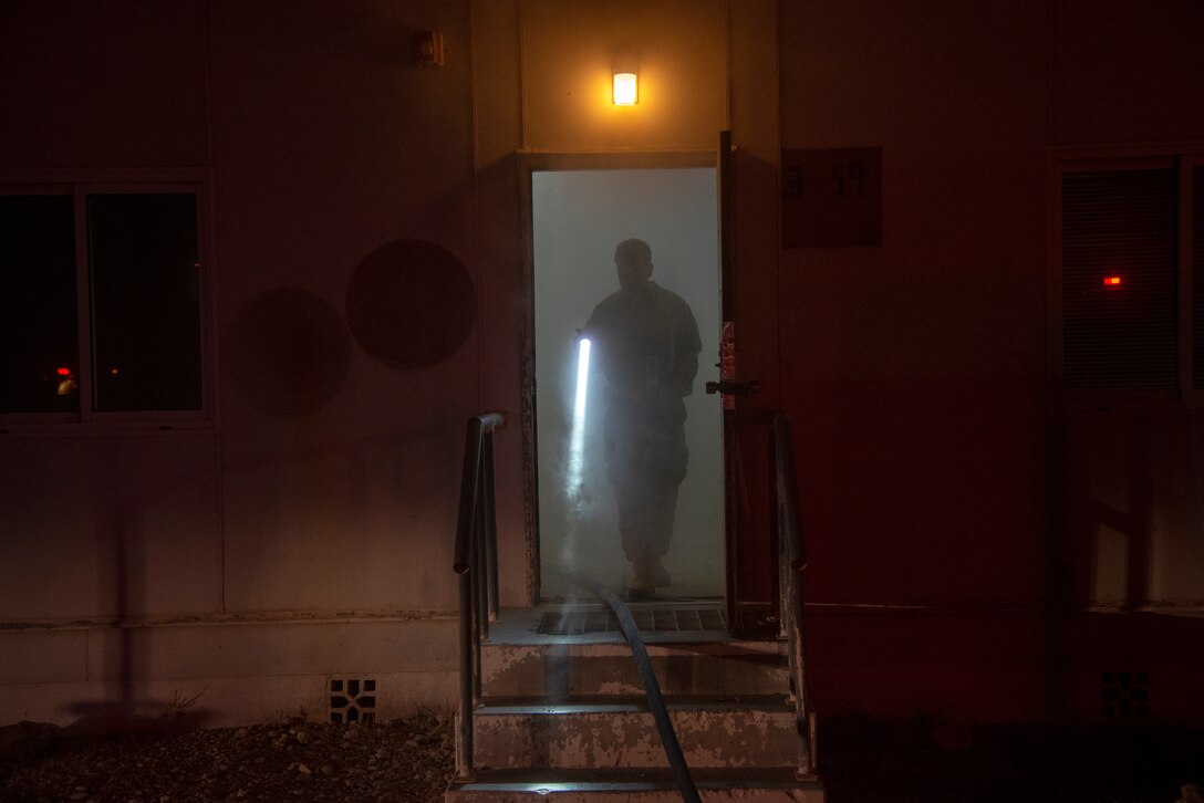 379th Air Expeditionary Wing Inspection Team (WIT) member walks out of a smoked-filled building during a fire safety exercise at Al Udeid Air Base, Qatar, July 24, 2020. WIT members evaluate and inspect Airmen and their units during exercises to keep their service members lethal and ready.