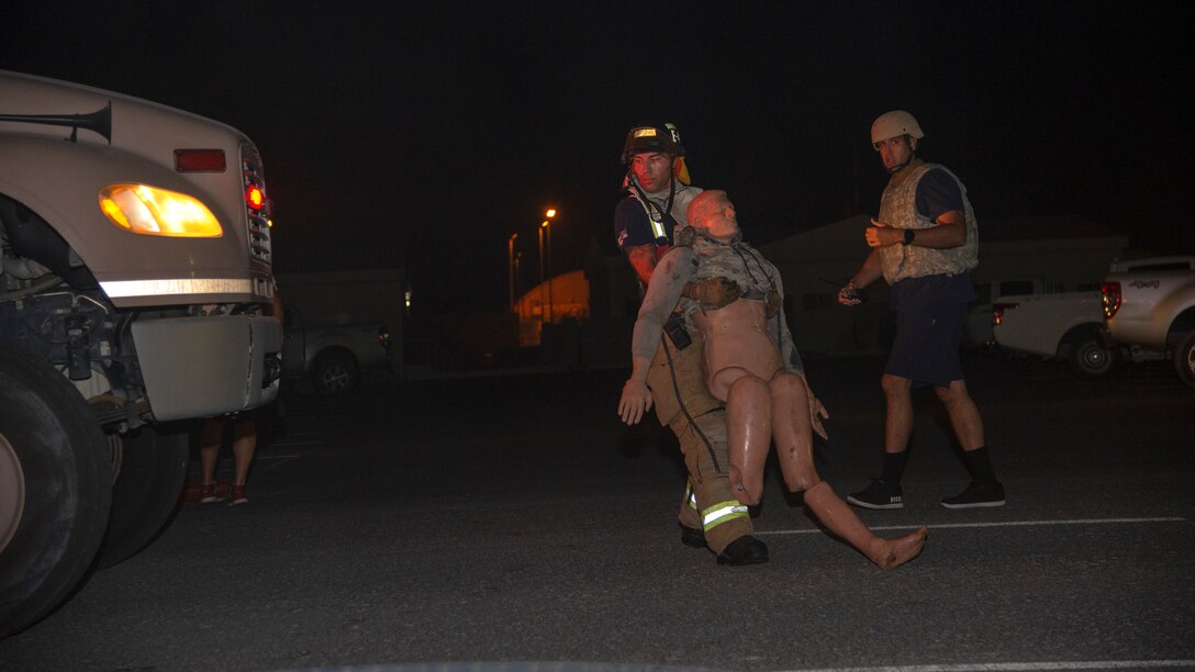 A 379th Air Expeditionary Civil Engineer Squadron Fire and Emergency Services Flight Airman carries a manikin off-scene during a simulated fire safety event during an exercise at Al Udeid Air Base, Qatar, July 24, 2020. The exercise included a fire safety event where Fire and Emergency Services responded to a simulated fire in a building with two unidentified manikins to rescue and provide simulated, emergency medical care.