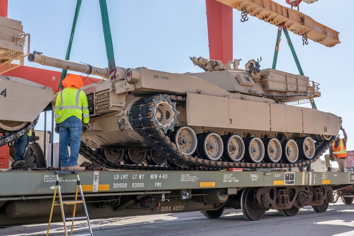 Civilian employees use hand signals to lower the M1A1 “Abrams” tank onto the rail cars aboard Marine Corps Logistics Base Barstow, Calif., July 7.