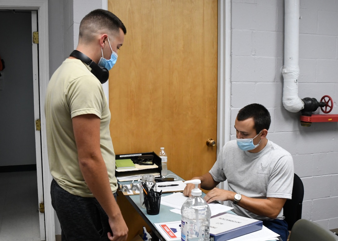 Staff Sgt. Nicholas Nihill, 104th Fighter Wing Fatality Search and Rescue Team Non-Commissioned Officer, signs Airman 1st Class David Buell, 104 FW egress technician, into the base fitness room July 22, 2020, at Barnes Air National Guard Base, Massachusetts. Due to the COVID-19 pandemic, wing members who choose to work out need to sign in and follow stricter guidelines in order to maintain a safe and healthy environment.  (U.S. Air National Guard photo by Senior Airman Sara Kolinski)