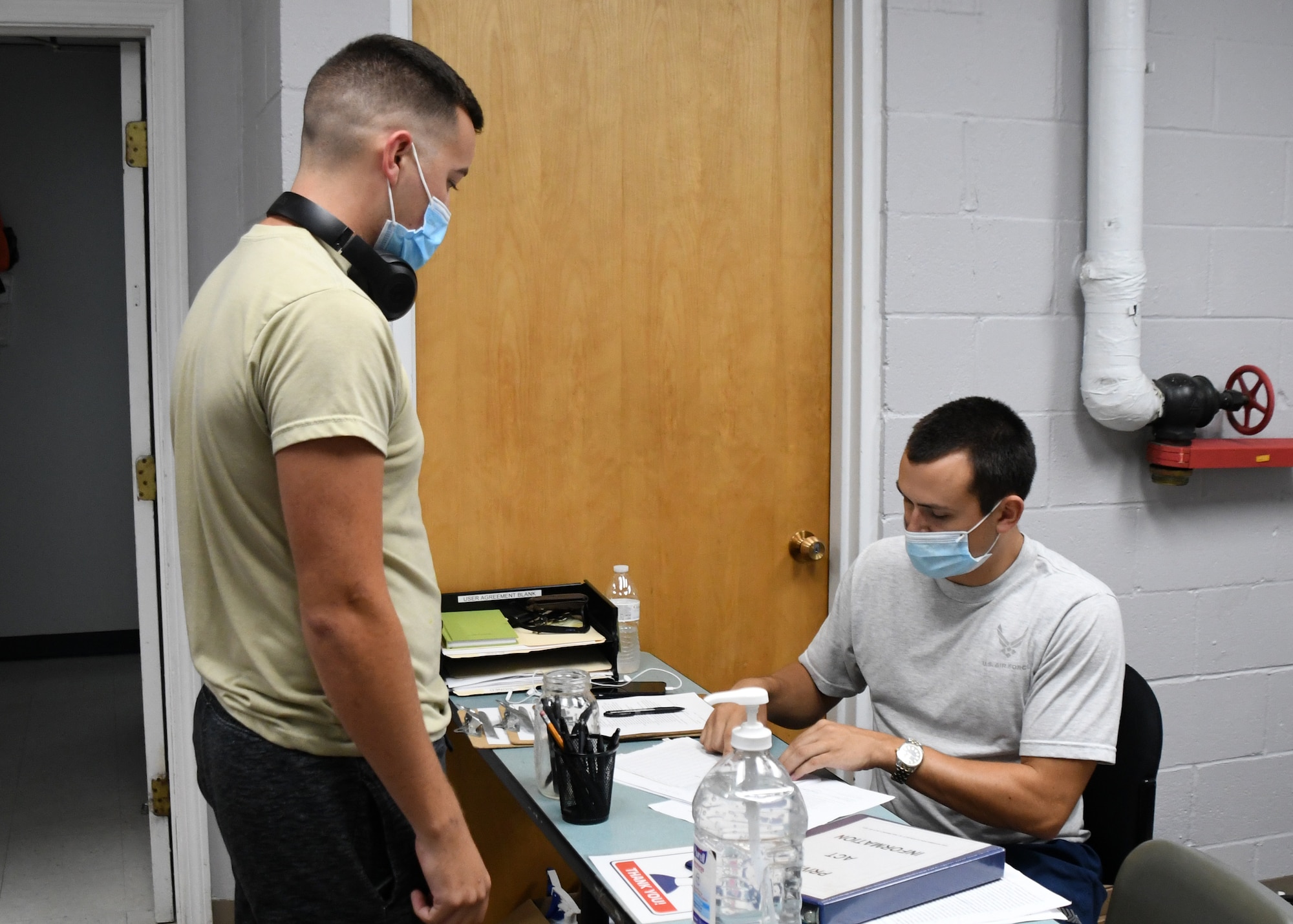 Staff Sgt. Nicholas Nihill, 104th Fighter Wing Fatality Search and Rescue Team Non-Commissioned Officer, signs Airman 1st Class David Buell, 104 FW egress technician, into the base fitness room July 22, 2020, at Barnes Air National Guard Base, Massachusetts. Due to the COVID-19 pandemic, wing members who choose to work out need to sign in and follow stricter guidelines in order to maintain a safe and healthy environment.  (U.S. Air National Guard photo by Senior Airman Sara Kolinski)