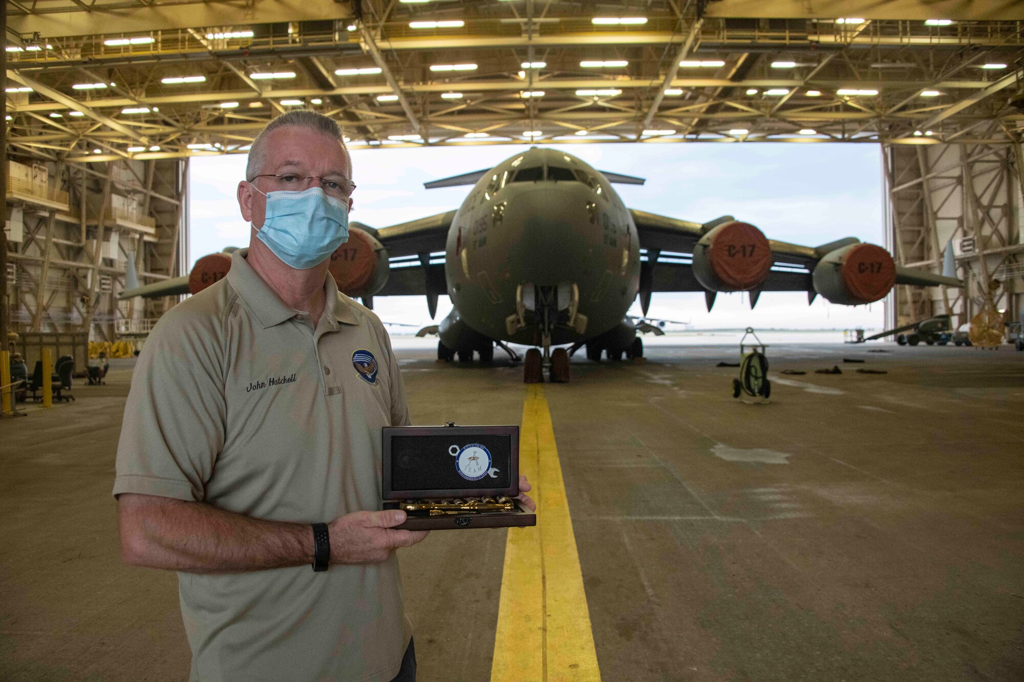 man holds award infront of aircraft