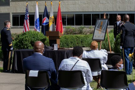 Brig. Gen. Mark S. Bennett, U.S. Army Financial Management Command commanding general, far left, presents a small version of the USAFMCOM flag to recently retired Sgt. Maj. Ronald Houston, U.S. Army Financial Management Command Operations senior enlisted advisor, far right, during Houston’s retirement ceremony at the Maj. Gen. Emmett J. Bean Federal Center in Indianapolis July 17, 2020. While the gift was presented by Bennett, it was from USAFMCOM’s employees in recognition of Houston’s more than 28 years of military service. (U.S. Army photo by Mark R. W. Orders-Woempner)