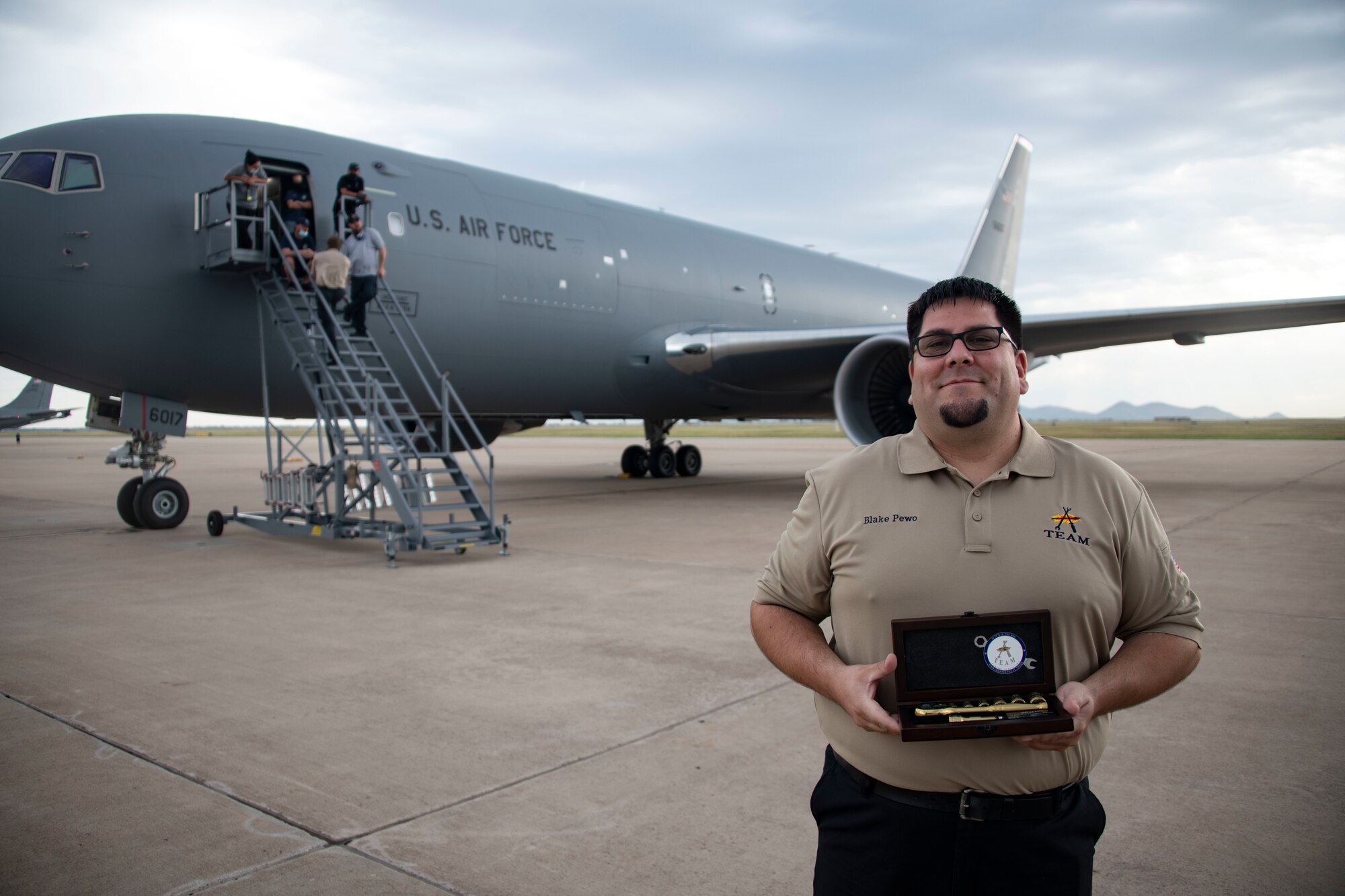 Man holds award infront of plane