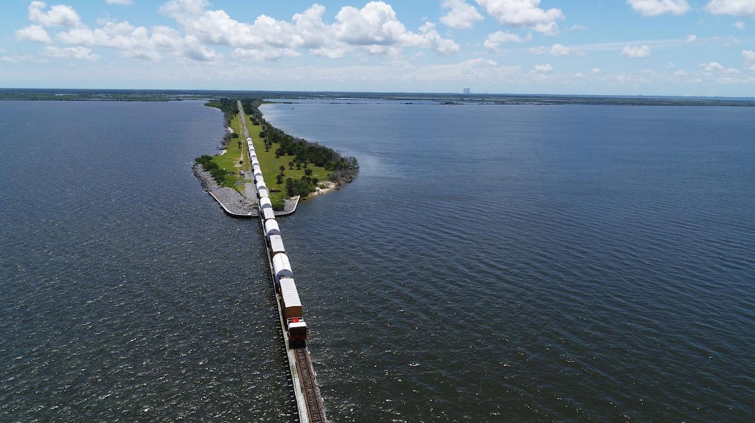 Photo of a train carrying a load over a bridge.