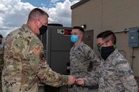 Maj. Gen. William Spangenthal, vice commander of Air Education and Training Command, coins Airman 1st Class Brian Hallock and Airman 1st Class Sebastian Flores, both from the 502nd Operational Support Squadron, during an immersion tour June 24, 2020, at Joint Base San Antonio-Lackland, Texas.