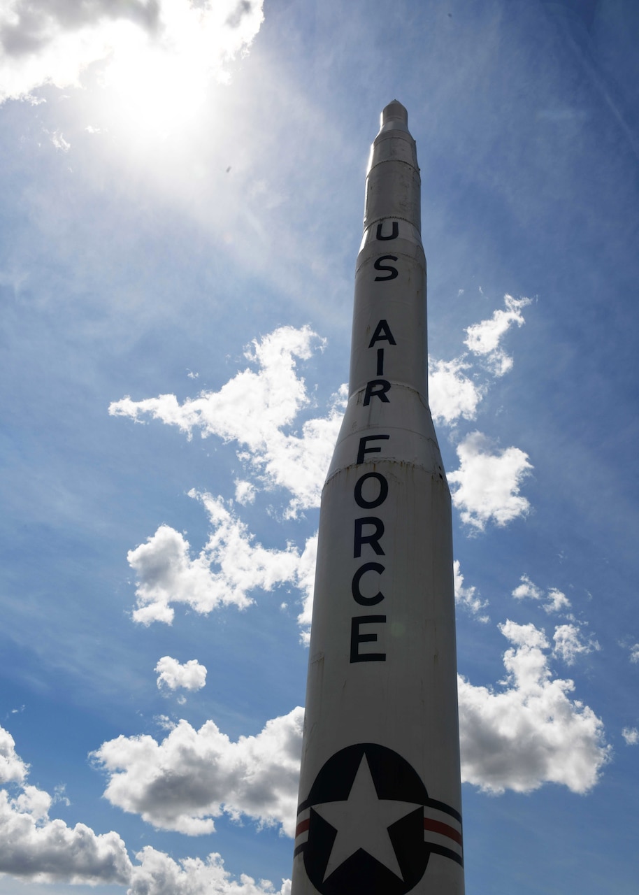 A missile replica stands against a blue sky.
