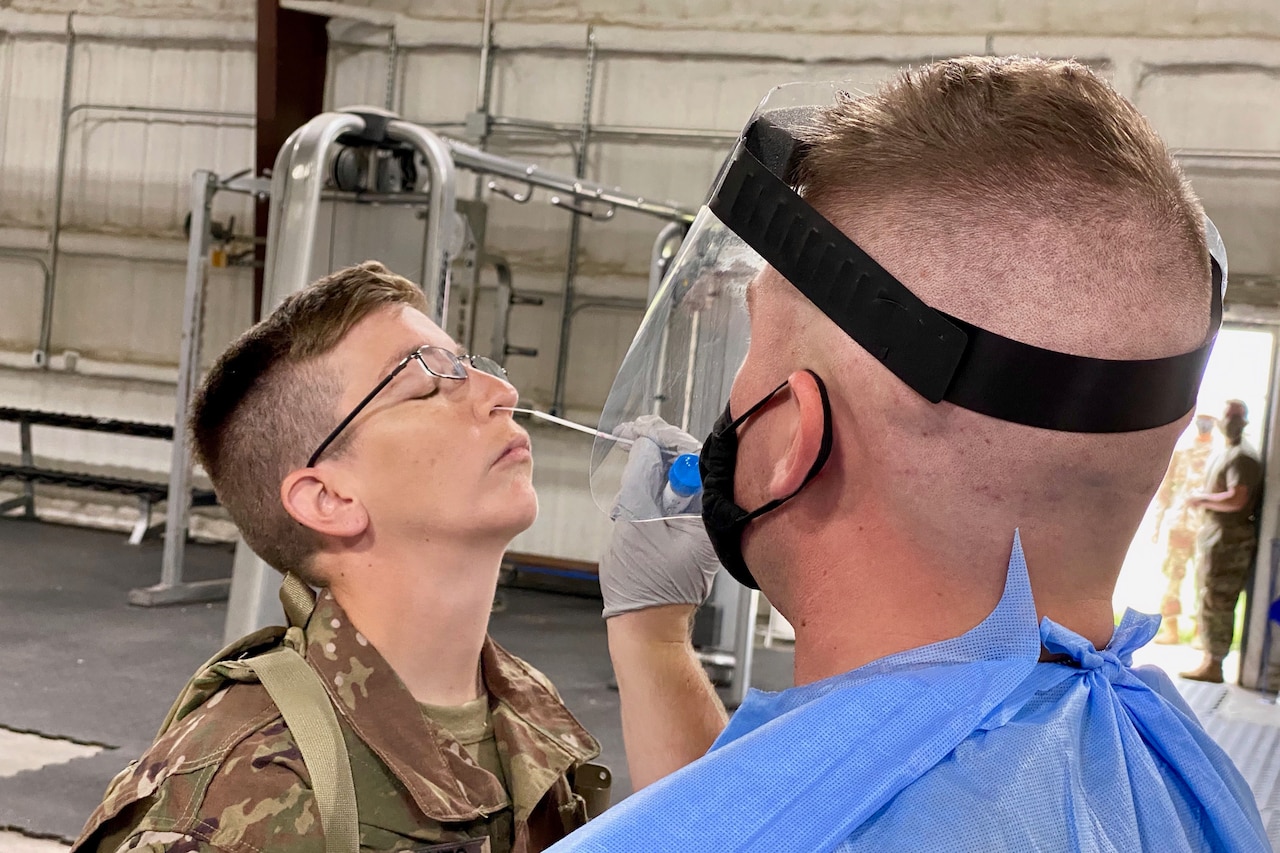 A medical professional swabs the nostril of a service member.