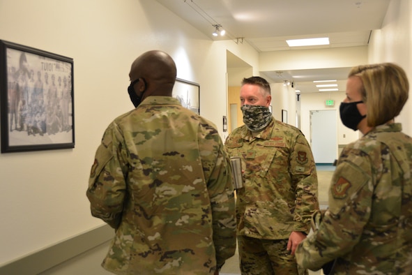 Photo of U.S. Air Force Col. Brett Paola, 477th Fighter Group commander discusses a historical World War II photo while Col. Travolis Simmons, 3rd Wing commander and Chief Master Sgt. Rebecca Bateman, 3rd WG command chief look on.