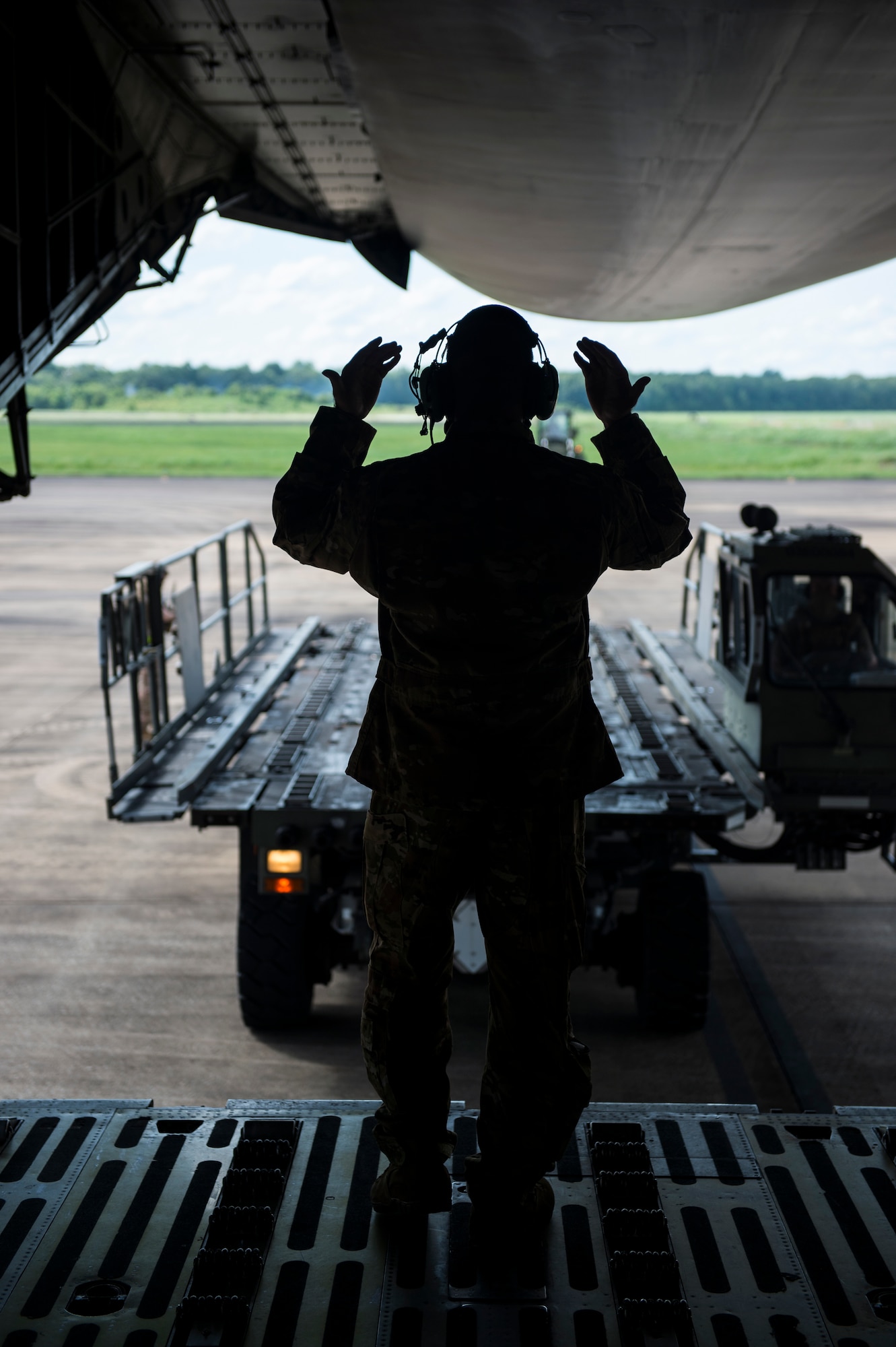 Airman 1st Class Jordan Gibson, 9th Airlift Squadron loadmaster, marshals a 60K Tunner cargo loader to a C-5M Super Galaxy July 29, 2020, at Alexandria International Airport, Louisiana. Air Force active-duty, Reserve, and Air National Guard Airmen as well as civilian counterparts participated in Exercise Swamp Devil to test their capabilities on responding to humanitarian aid and disaster relief missions during the COVID-19 pandemic. (U.S. Air Force photo by Staff Sgt. Sarah Brice)