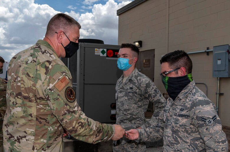 Maj. Gen. William Spangenthal, vice commander of Air Education and Training Command, coins Airman 1st Class Brian Hallock and Airman 1st Class Sebastian Flores, both from the 502nd Operational Support Squadron, during an immersion tour June 24, 2020, at Joint Base San Antonio-Lackland, Texas.
