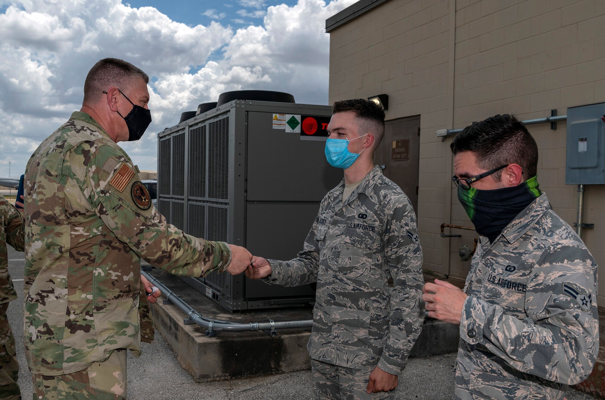 Maj. Gen. William Spangenthal, vice commander of Air Education and Training Command, coins Airman 1st Class Brian Hallock and Airman 1st Class Sebastian Flores, both from the 502nd Operational Support Squadron, during an immersion tour June 24, 2020, at Joint Base San Antonio-Lackland, Texas.