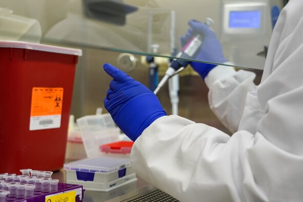 A military technician processes a petri dish.