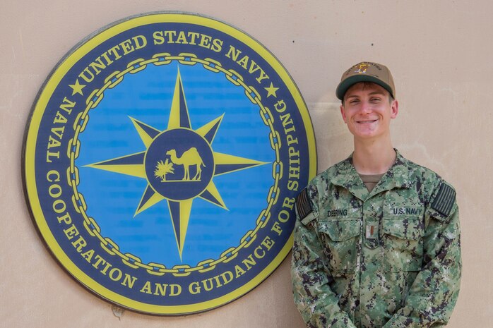 200625-N-IO414-1041 NAVAL SUPPORT ACTIVITY BAHRAIN (June 25, 2020) Ensign Jonathon Deering poses for a photo in front of U.S. Naval Forces Central Command’s Naval Cooperation and Guidance for Shipping (NCAGS) headquarters. NCAGS serves as a communication link between merchant and military vessels and is made up entirely of U.S. Navy reservists, many of whom are professional merchant marines who leverage their civilian expertise and experience when they report for duty.