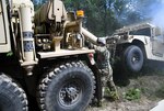 Spc. Darrin Hilts, a wheeled vehicle mechanic with the Michigan Army National Guard's 1073rd Maintenance Company,  works the hydraulics of an M984 HEMTT wrecker while preparing to tow a Humvee as part of a training mission during exercise Northern Strike at Camp Grayling, Michigan, July 27, 2020.