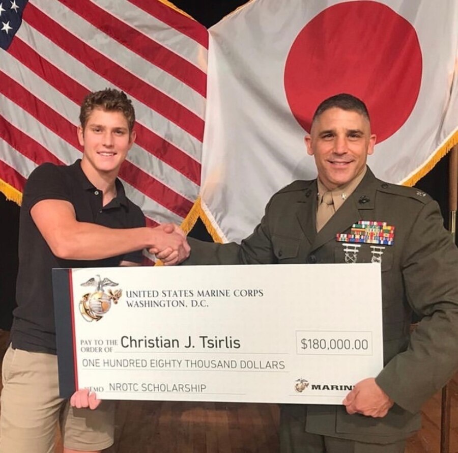 Lt. Col. Christopher Tsirlis presents his son, Christian, with the $180,000 Naval Reserve Officer Training Corps scholarship during his high school awards night in 2019.