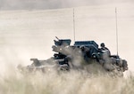 A military vehicle maneuvers through a training area.