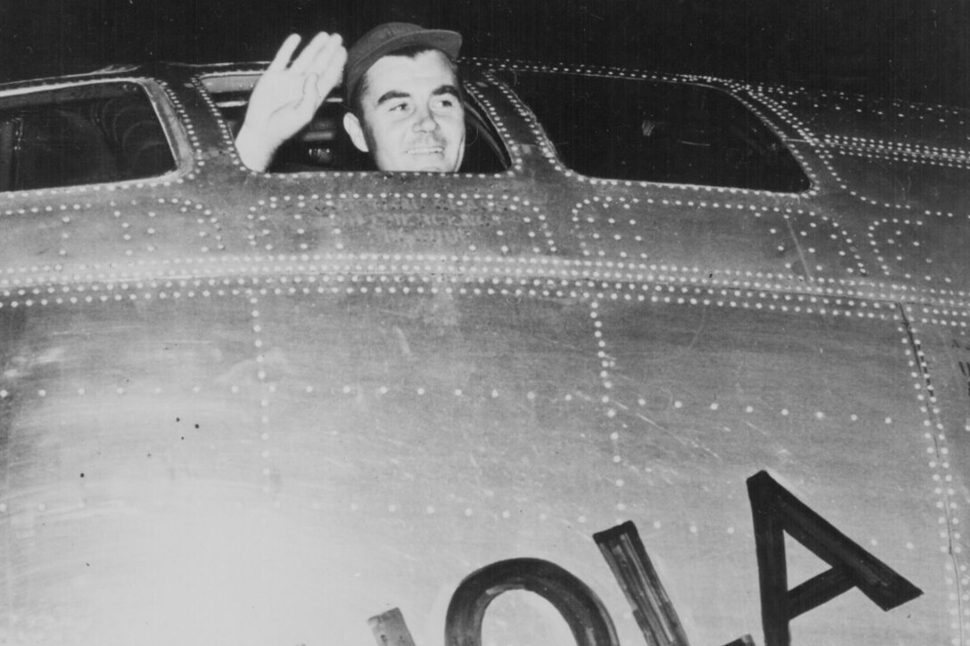 A man waves from the cockpit of a plane.