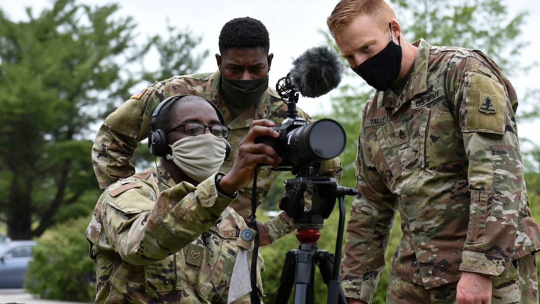 DINFOS students observe an image through the lens of a camera.