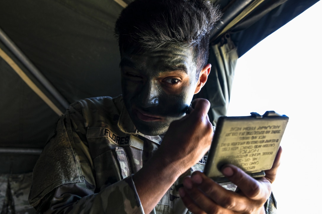 A soldier stares into a mirror while painting his face.