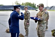 U.S. Air Force Senior Airman Javier Barraza, a 354th Force Support Squadron ceremonial guardsman, salutes a flag held by Staff Sgt. Anthony Vega, the 354th Civil Engineer Squadron Explosive Ordnance Disposal (EOD) flight noncommissioned officer in charge of operations, during a ceremony on Eielson Air Force Base, Alaska, July 31, 2020. Every year, EOD Airmen ruck 220 miles from Eielson AFB to the Arctic Circle to honor members of the EOD community who paid the ultimate sacrifice. (U.S. Air Force photo by Senior Airman Beaux Hebert)