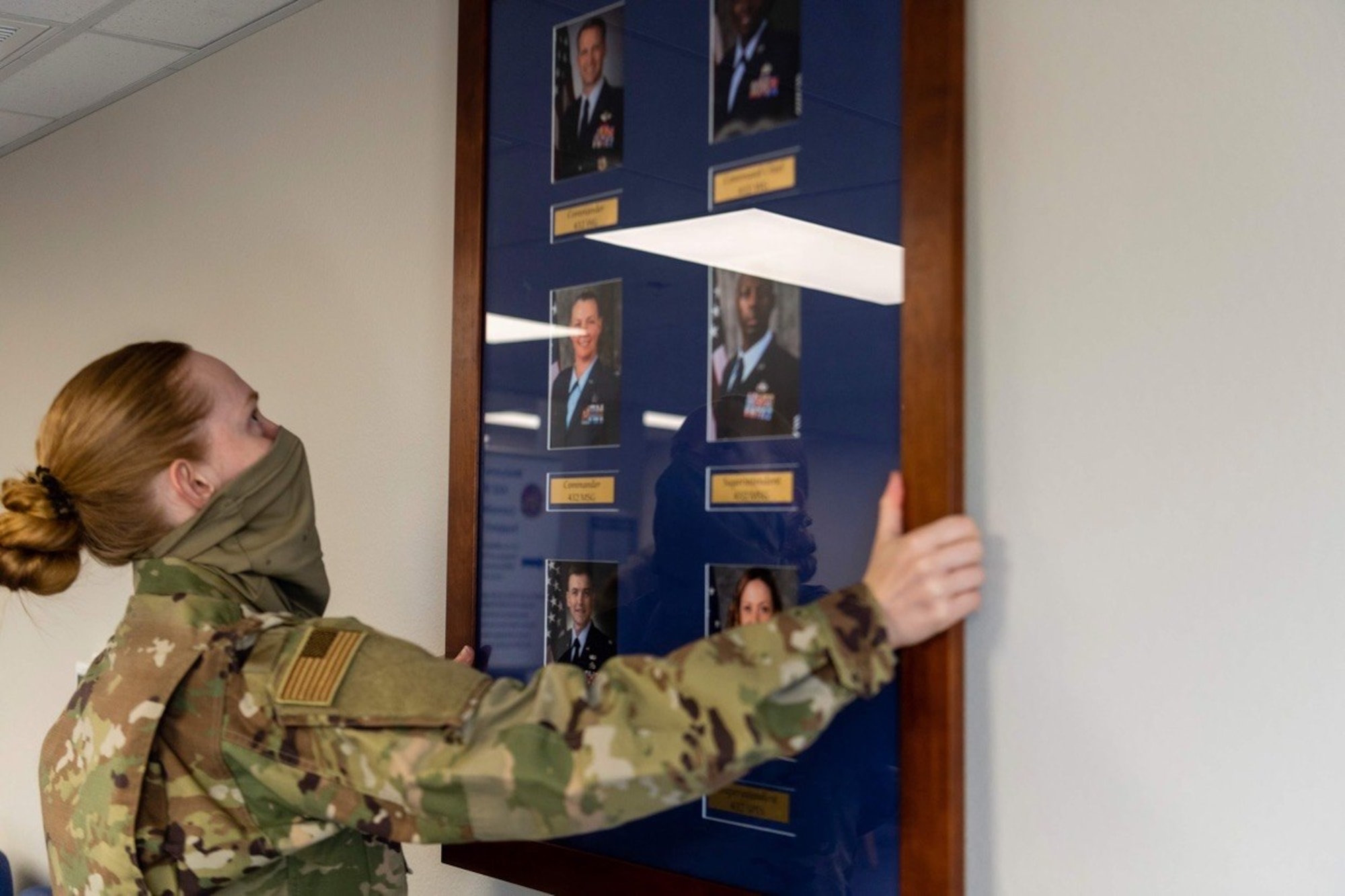 Airman 1st Class Alexandria, force management technician with the 432nd Support Squadron, carefully places a command board on the wall of the newly renovated consolidated support center at Creech Air Force Base.