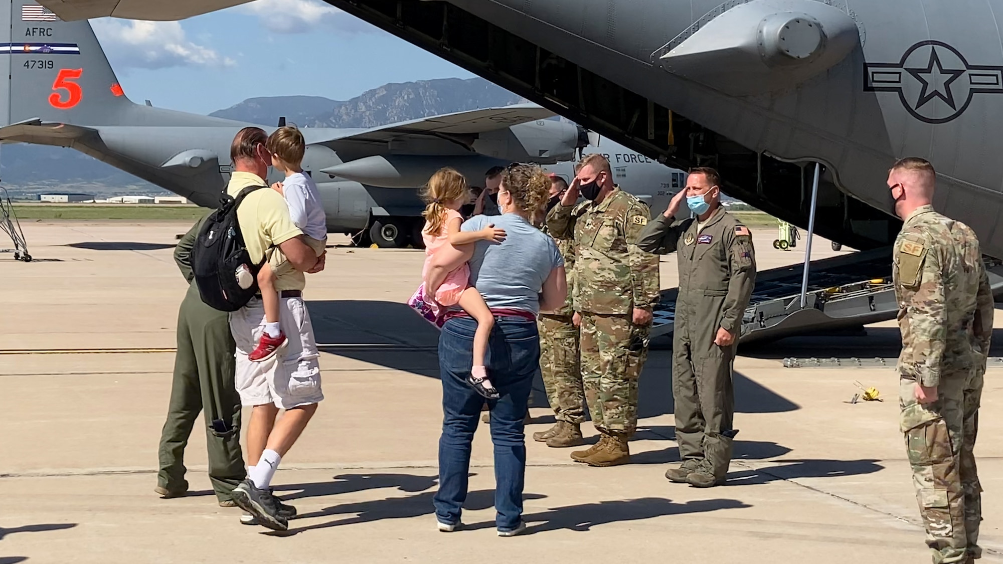 People stand on flightline next to large plane.