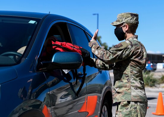 An Airman hands out school supplies.