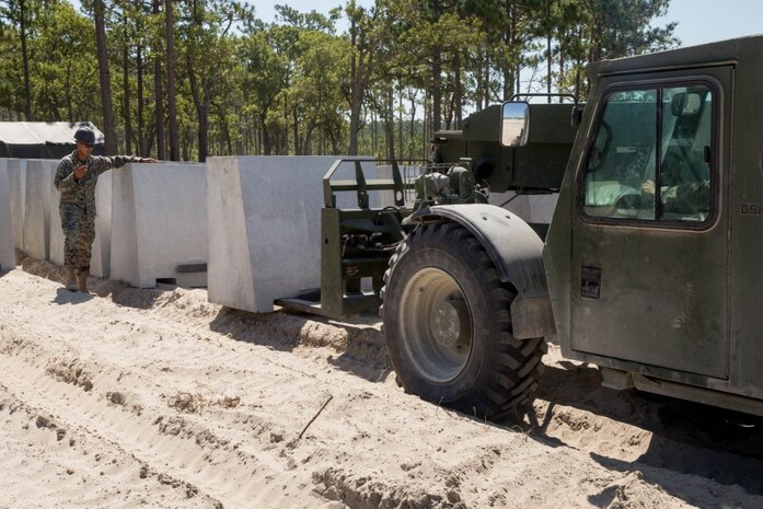 U.S. Marine Corps Lance Cpl. Martin Lebron, a heavy equipment operator with 2d Engineer Support Battalion, guides a forklift operator to place a barricade on Camp Lejeune, North Carolina, July 27, 2020. Range G-6 was modified by 2d Combat Engineer Battalion to allow for advanced company level offensive and defensive operations, previously not possible on Camp Lejeune. (U.S. Marine Corps photo by Cpl. Elijah J. Abernathy)