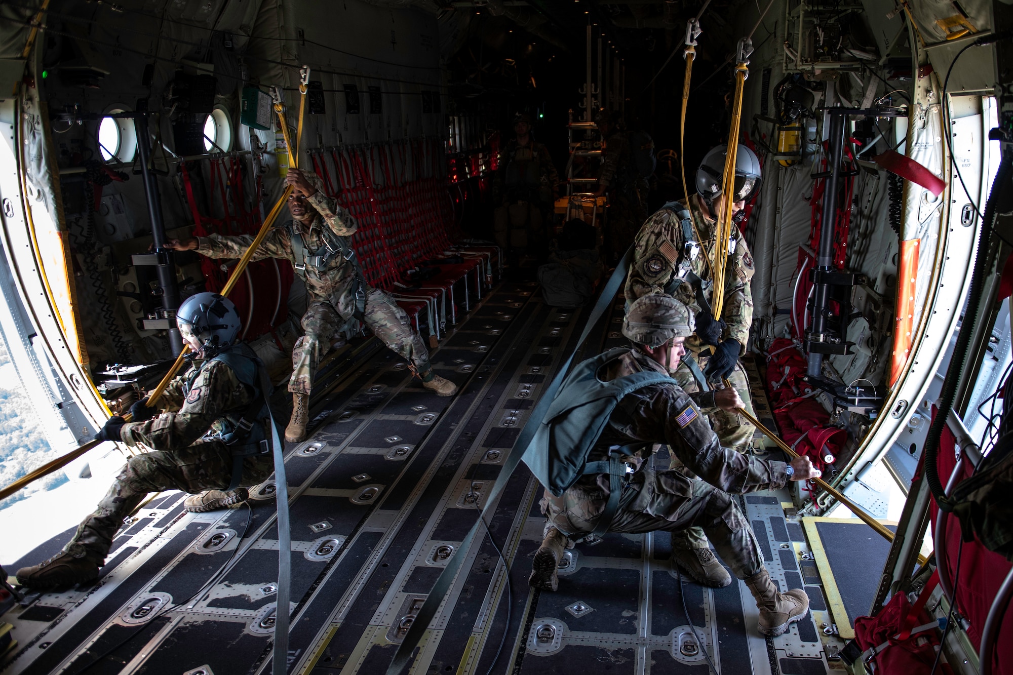 U.S. Air Force loadmasters assigned to the 37th Airlift Squadron and U.S. Army jumpmasters assigned to the 5th Quartermaster, Rhine Ordnance Barracks, pull static lines into a C-130J Super Hercules.