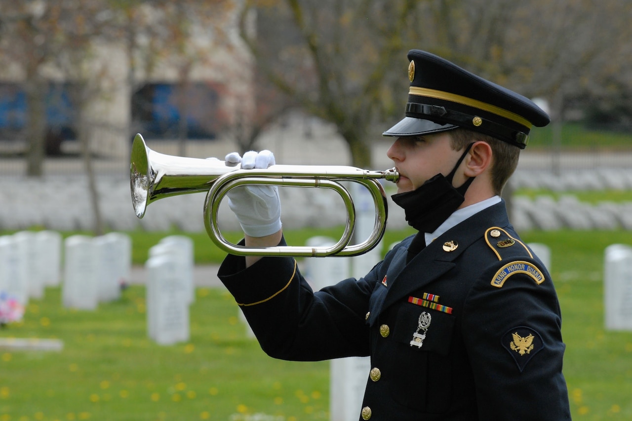Honor guard soldier plays a trumpet at a military funeral.